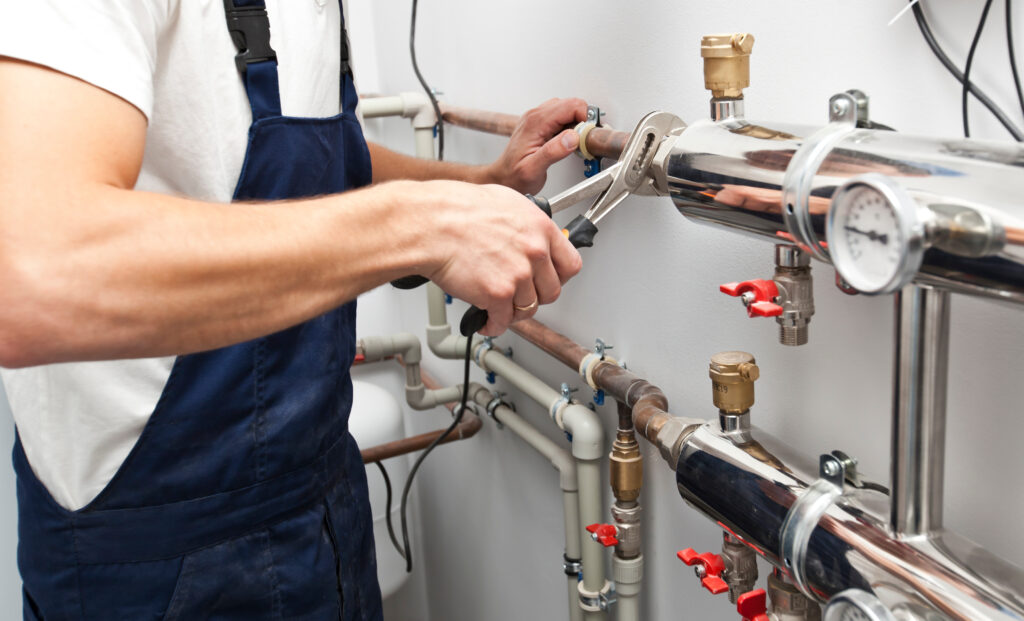 A plumber wrenching on a pipe